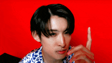 a young man in a blue and white shirt covering his face with his hand