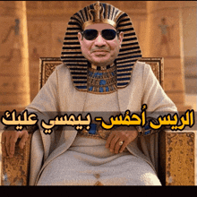 a man wearing sunglasses and a pharaoh 's hat is sitting in a chair