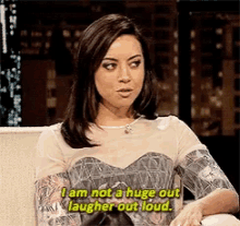 a woman is sitting on a couch saying i am not a huge out laugher out loud