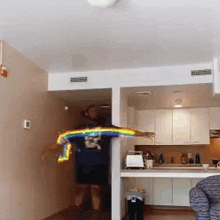 a man in a blue shirt with a rainbow on his shirt is jumping in the air