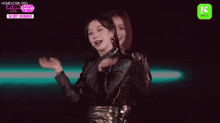 a woman in a black leather jacket is dancing on a stage with another woman .