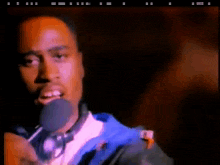 a man in a blue jacket is holding a microphone in his hand .