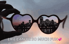 a person is holding a pair of heart shaped sunglasses with a city skyline reflected in them