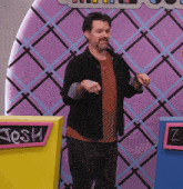a man is standing in front of a wall with the name josh on it