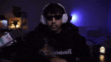 a man wearing headphones and sunglasses stands in front of a microphone that says ao on it