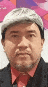 a man with a beard and gray hair is wearing a wig .