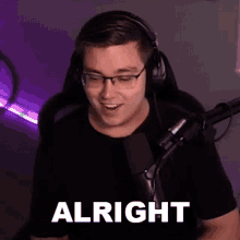 a man wearing headphones and glasses is sitting in front of a microphone and making a funny face .