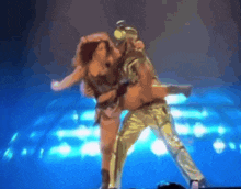 a man and woman are dancing on a stage in front of a blue background