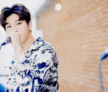 a young man singing into a microphone while wearing a shirt that says ' a ' on it