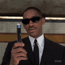 a man in a suit and tie is holding a device that says starz on the bottom