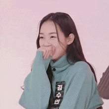 a woman wearing a blue sweater with chinese writing on it is laughing .