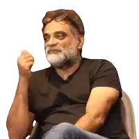 a man with glasses and a beard is sitting in a chair