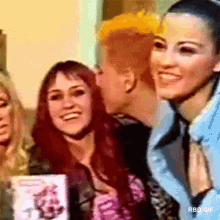 a group of women are standing next to each other and smiling . one of the women has a shaved head .