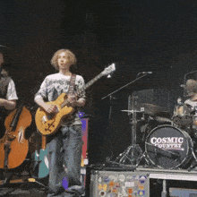 a man playing a guitar on stage in front of a drum that says cosmic country