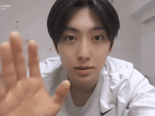 a young man wearing a white nike shirt is reaching out towards the camera