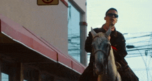 a man wearing sunglasses is riding a white horse