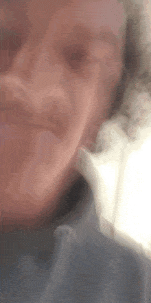 a close up of a person 's face with smoke coming out of their nose