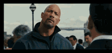 a bald man with a beard is standing in front of a crowd of people