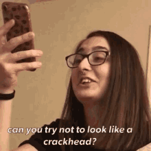 a woman wearing glasses and a nose ring is taking a selfie with her phone .