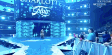 a woman on a stage with a sign that says charlotte flair behind her