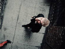 a man in a black suit is walking down a sidewalk
