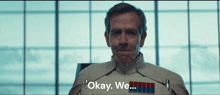 a man in a military uniform says " okay we " in front of a window