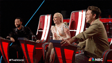 a group of people sitting in front of a screen that says the voice