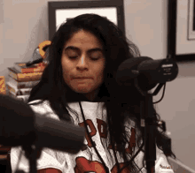 a woman wearing a jersey with the letter p on it is sitting in front of a microphone