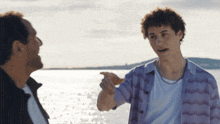 a man in a purple shirt talks to another man in a white shirt