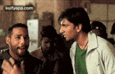 a group of men are standing next to each other in a room and talking to each other .
