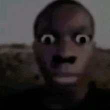 a blurry picture of a man 's face with a mustache and a big mouth .