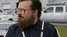 a man with glasses and a beard is wearing a blue shirt