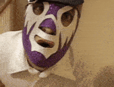 a man wearing a purple and white mask with the letter r on his face