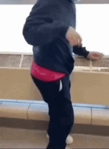 a person wearing a black jacket and black pants is standing in front of a wall .
