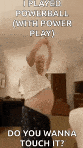 a man is standing in a living room with his arms in the air .