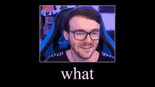 a man with glasses and a beard is sitting in a gaming chair and smiling .