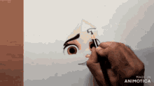 a person is drawing a face with a pencil on a piece of paper that says made in animatica