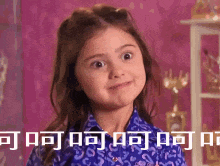 a little girl is making a funny face in front of a purple wall .