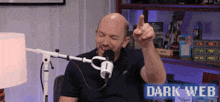 a bald man is sitting in front of a microphone with the words dark web behind him
