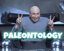 a bald man is giving a peace sign in front of a sign that says paleontology