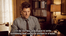 a man in a plaid shirt and tie is sitting at a desk talking