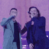 two men in suits are singing into microphones