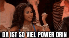 a woman is sitting in a crowd with her fist in the air and the words `` da ist so viel power drin '' .