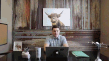 a man sits at a desk with an apple laptop on it