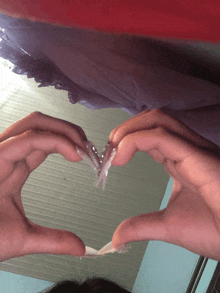 a person is making a heart with their hands