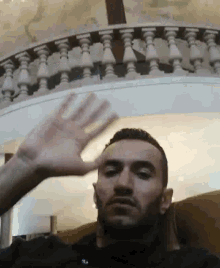 a man waving his hand in front of a balcony railing