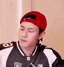 a man wearing a red hat and a black and white jersey is making a funny face .