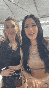 two women are posing for a picture and one is wearing a tan top