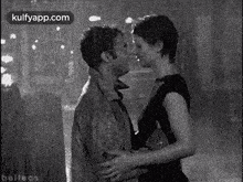 a man and woman are kissing in the rain in a black and white photo .