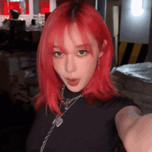 a woman with red hair is wearing a black shirt and a heart necklace